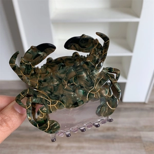 Détail de la pince à cheveux crabe créative avec texture marbre vert et accents dorés