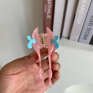 Detail of a pink and blue butterfly hair claw clip with marble texture and metal spring