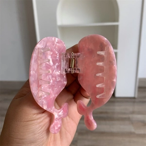 Detailed shot of whale tail hair claw clip in pink marble acetate with metal spring