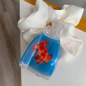 Macro detail of acrylic crab hair claw clip with creative goldfish bag design elements