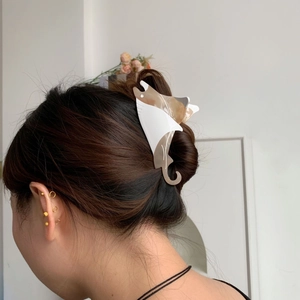 Detail view of a stingray hair claw clip in amber and white acetate on a hair bun