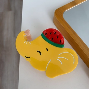 Détail d'une pince à cheveux éléphant jaune avec un petit accessoire de pastèque
