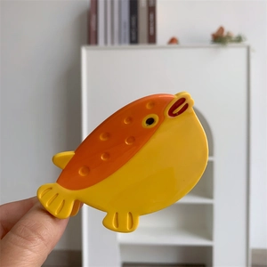 Détail d'une pince à cheveux poisson jaune et orange en acétate avec texture mouchetée
