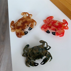 Gros plan de pinces à cheveux crabe ambre et rouge avec motifs marbrés dorés