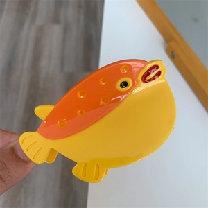 Détail de la pince à cheveux en forme de poisson-globe jaune en acétate brillant à pois