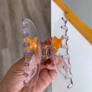 Detail of butterfly hair claw clip with purple gradient and orange starfish decorative charms