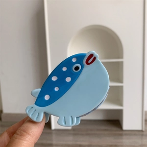 Détail de la pince à cheveux en forme de poisson lune bleu en acétate avec pois blancs