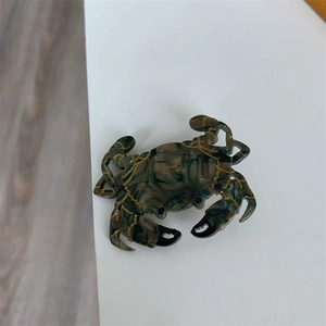 Détail d'une grande pince à cheveux crabe en acétate marbré vert et accents dorés