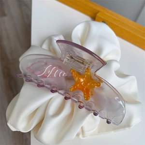 Close-up of translucent purple acetate hair claw with orange starfish and pearly shells