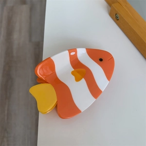 Vue détaillée d'une pince à cheveux mignonne en acétate en forme de poisson rayé orange