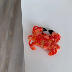 Vue détaillée d'une pince à cheveux crabe en acétate marbré orange aux accents dorés