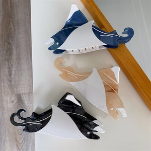 Three creative manta ray hair claws in navy, amber, and marble acetate on a white table