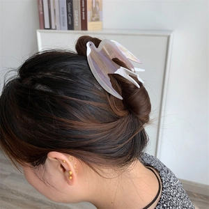 Détail d'une pince à cheveux hirondelle blanc nacré sur un chignon élégant