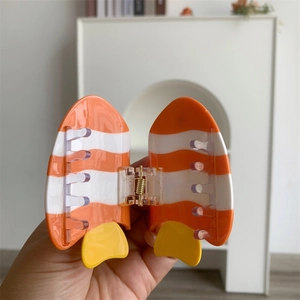 Détail d'une pince à cheveux poisson-clown orange à rayures blanches et fini brillant