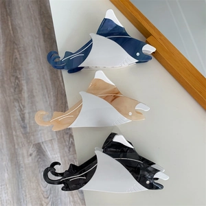 Artistic stingray hair claws in marble blue, pink, and black acetate displayed on a desk