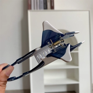 Close-up of manta ray hair claw made of deep blue and white acetate with a metal spring