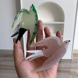 Détail des pinces à cheveux hirondelle en acétate aux couleurs vert et rose pastel