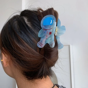 Vue détaillée d'une pince à cheveux astronaute en acétate bleu sur cheveux bruns