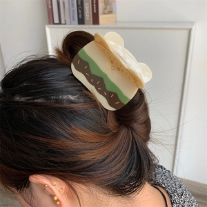 Bonita pinza para el pelo de acetato beige con forma de oso puesta en un peinado