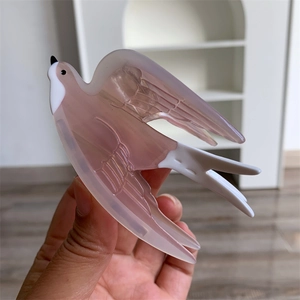Détail de la texture d'une pince à cheveux hirondelle en acétate rose translucide