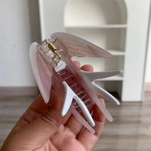 Détail de la pince à cheveux hirondelle avec dégradé rose et ressort doré