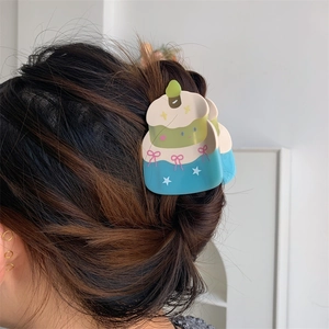 Detailed view of creative birthday cake hair claw with pink bow on dark brown hair