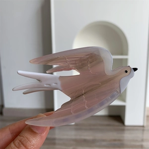 Gros plan sur la pince à cheveux hirondelle en acétate rose et blanc translucide