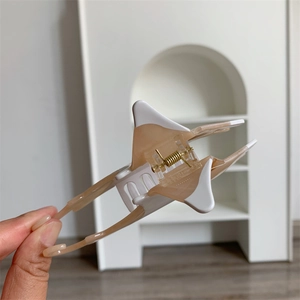 Macro detail of bicolored acetate stingray hair claw clip with golden metal spring
