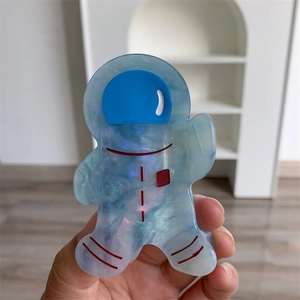 Gros plan sur la pince à cheveux astronaute en acétate bleu translucide avec effet nacré