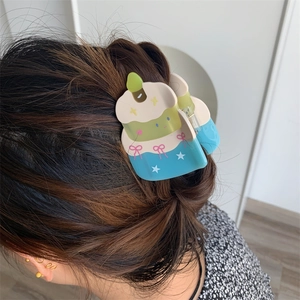 Detailed view of a cake-shaped acetate hair claw clip worn on long brown hair