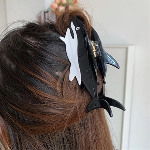 Macro view of a large black and white shark-shaped hair claw clip for thick hair