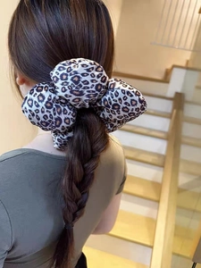 Close-up of leopard print velvet scrunchie worn on a braided ponytail hairstyle