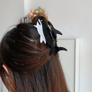 Detailed view of an orca shaped hair claw clip styled on a woman's hair in a home setting
