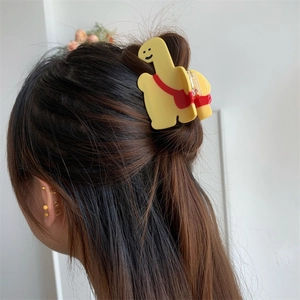 Vue détaillée d'une pince à cheveux girafe jaune avec sac à dos portée sur les cheveux