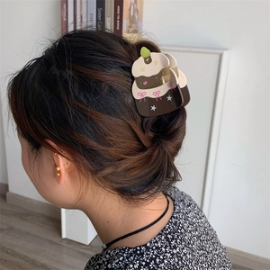 Detail view of acetate cake hair claw with pink bow and star charms on hair