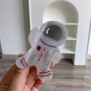 Détail de la pince à cheveux astronaute en acétate nacré avec motifs de lignes rouges