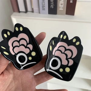 Close-up of gloss resin hair claws featuring cute black and pink cat paw designs
