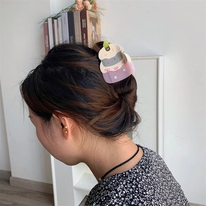 Detail showing cartoon birthday cake hair claw clip with pink bow design in a hairstyle