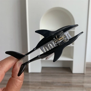 Close-up of a shark-shaped hair claw clip in black and white glossy resin finish