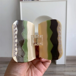 Detalle de pinza para el pelo grande de acetato con ondas marrón verde y resorte dorado