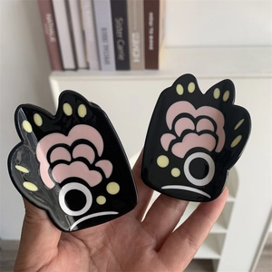 Detail showing two glossy acetate bear paw hair claws with abstract pink and white patterns