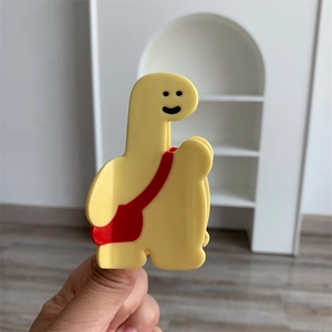 Détail de la pince à cheveux girafe jaune avec motif de sangle de sac à dos rouge