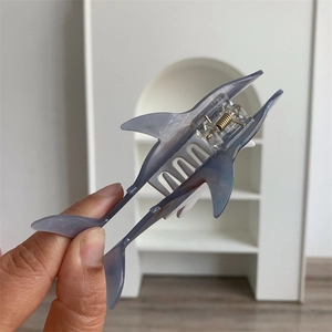Macro detail of shark-shaped hair claw clip in translucent grey acetate with marble texture