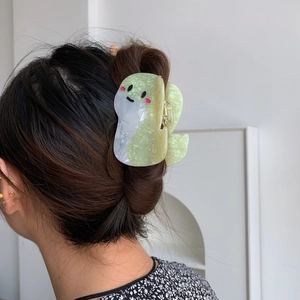Dettaglio della graziosa molletta per capelli a forma di serpente in acetato verde su modella
