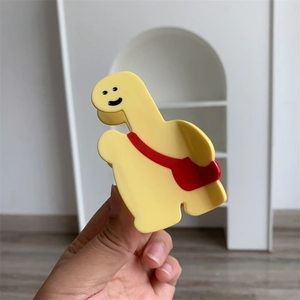 Vue détaillée d'une pince à cheveux girafe jaune avec un petit sac à dos rouge