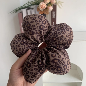 Detailed view of a large leopard print velvet hair scrunchie with soft fluffy texture