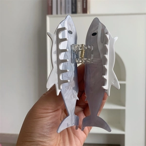 Detail view of the lilac translucent acetate fish-shaped hair claw clip with gold spring