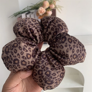 Detail of soft leopard print velvet hair scrunchie with fluffy pleated texture and warm brown tones