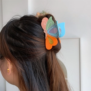Nahaufnahme einer bunten Acetat-Schmetterling-Haarklammer mit Strasssteinen am Haarknoten
