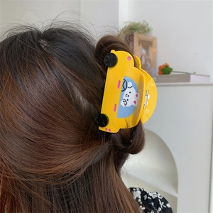 Detailed view of a yellow car-shaped hair claw clip with a cute rabbit on dark hair
